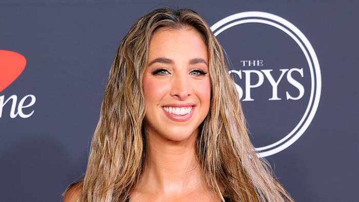 Katie Austin poses in a black dress and wears her dirty blonde hair in a beach wave.